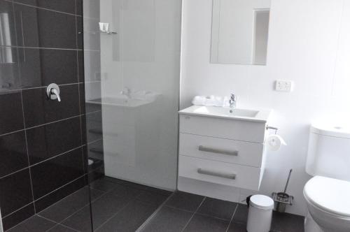 a bathroom with a shower and a sink and a toilet at Queens Head Hotel in West Hobart
