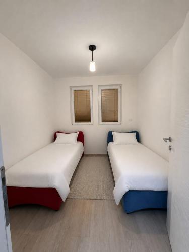 two beds in a small room with two windows at Villa Calypso Sarajevo in Sarajevo