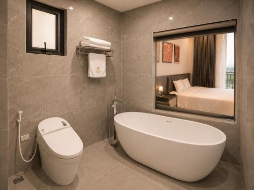 a bathroom with a toilet and a bath tub at Coline Hotel & Aparment in Ninh Binh