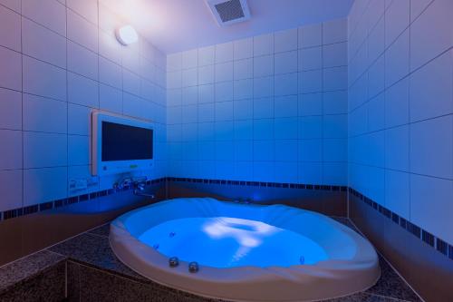 a blue tub in a bathroom with a tv at HOTEL Karin in Tokyo