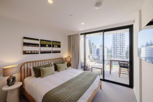 a bedroom with a large bed and a balcony at Esprit Holidays Rainbow Bay in Gold Coast