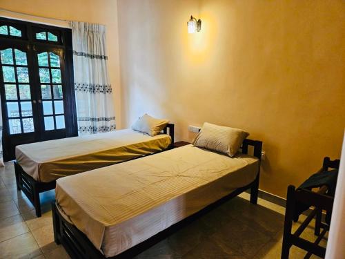 two beds in a room with a window at Deke Kanuwa in Kandy