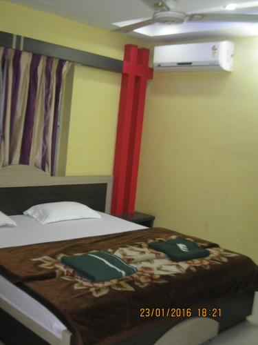 a bedroom with a bed with a red cross on the wall at Hotel Srikrishna International in Tarapith