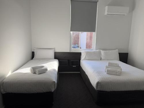 two twin beds in a room with a window at Queens Head Hotel in West Hobart