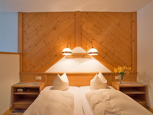 a bedroom with two beds with a large headboard and lights at Edelweiss 101 - Typ B in Fontanella