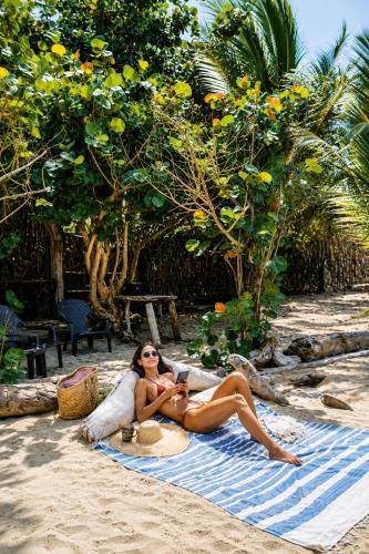 a woman in a bikini sitting on a towel on the beach at Las Dunas Beach house en Santa veronica cerca a la playa in Juan de Acosta