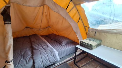 a small bed in a tent with a table at Jolotundo Glamping and Edupark in Sagi
