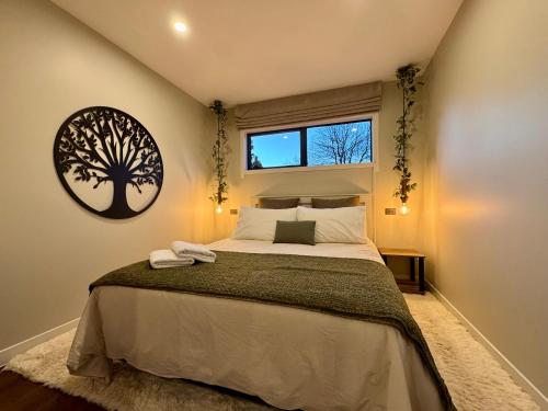 a bedroom with a bed with a tree picture on the wall at Modern Mountain Retreat in Ohakune