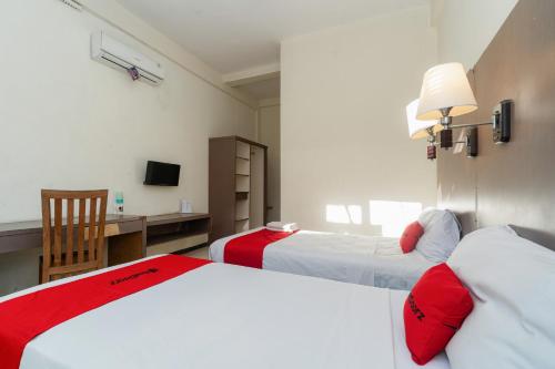 a hotel room with two beds and a desk at RedDoorz near Gubeng Station Surabaya in Bagongpatar