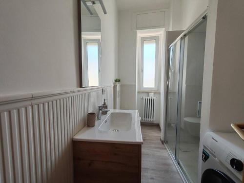 a white bathroom with a sink and a mirror at Cozy apartment overlooking the main square in Orsogna