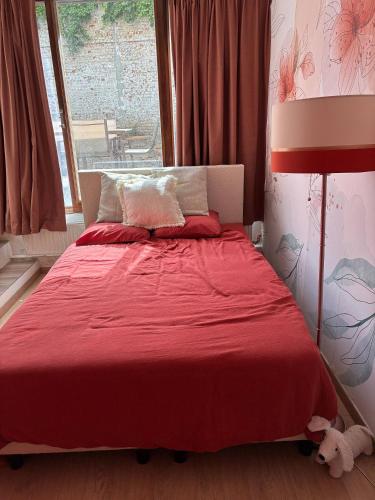 a bedroom with a red bed with a red blanket at Tastefully-decorated bedroom with garden access in Brussels