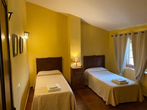 a yellow room with two beds and a window at Detached 4 Bedroom Villa with Pool in Valencia de Alcántara