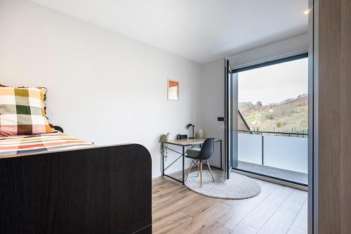 a bedroom with a bed and a desk and a balcony at CasaGurutze in Elizalde