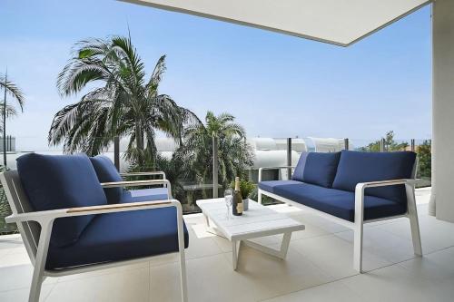 a patio with blue chairs and a table and palm trees at Coastal Chic with Heated Pool Quiet Location in Sunshine Beach