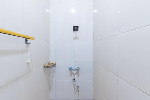a bathroom with a shower with white tiles at Urbanview Hotel Sany Cirebon in Tangkil