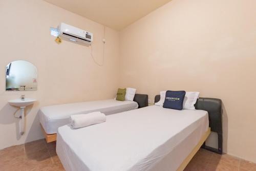 two beds in a room with a sink and a mirror at Urbanview Hotel Sany Cirebon in Tangkil