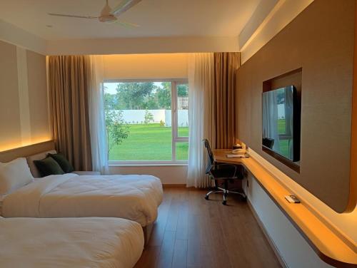 a hotel room with two beds and a television at Metta Shaanti Hotel Shravasti in Khargupur