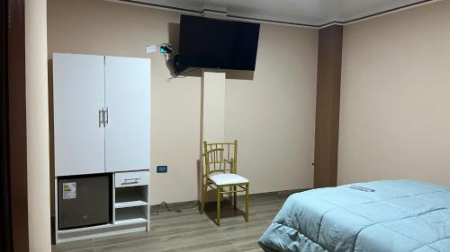 a bedroom with a bed and a tv and a chair at El Refugio del Rey in Cajamarca