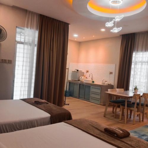 a room with two beds and a table and a kitchen at Sekebun Bunga in Tumpat