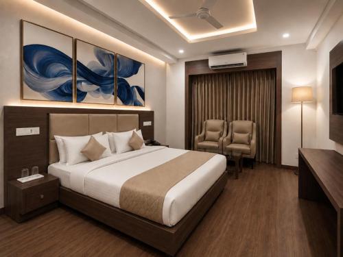 a hotel room with a bed and two chairs at Sapphire Hotel & Convention Centre in Baddi