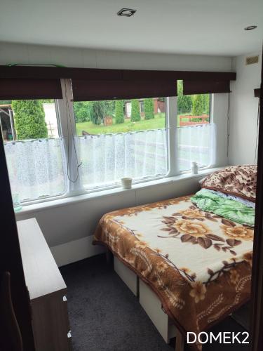a small bedroom with a bed and two windows at Gospodarstwo Agroturystyczne RYBAKÓWKA in Warlubie