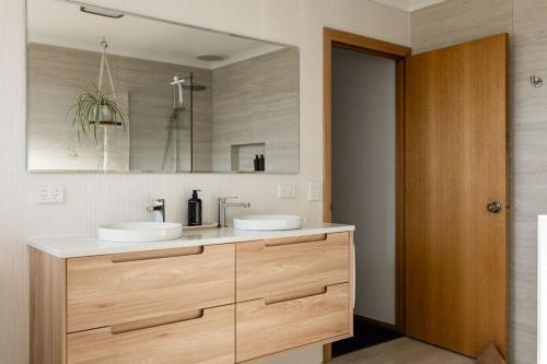 a bathroom with two sinks and a large mirror at Drift - Watch the world go by in Scamander