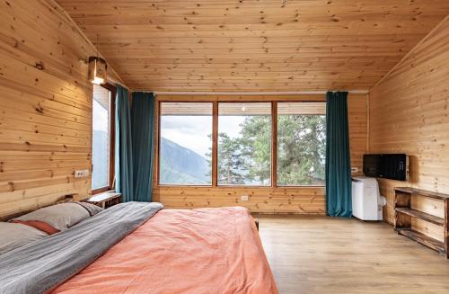 a bedroom with a bed and a large window at Heshkili huts and cabins Svaneti in Keshkili