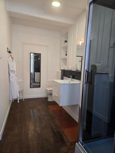 a white bathroom with a sink and a mirror at L'Argonnière in Buzancy