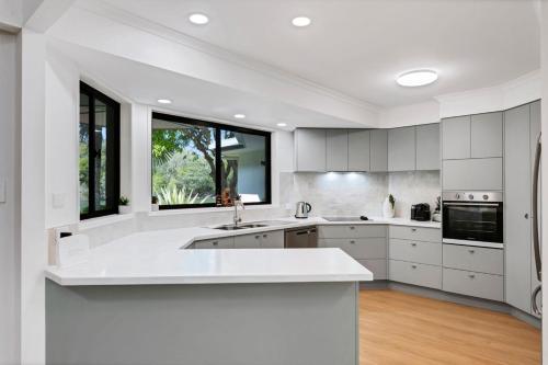 a kitchen with white cabinets and a large window at Wyuna Drive 53 in Noosaville