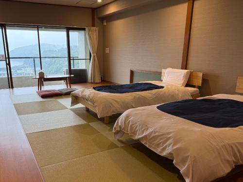 a hotel room with two beds and a window at Rustic Retreat リトリート真鶴 in Manazuru