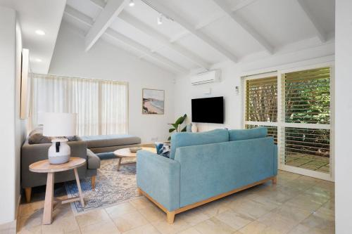 a living room with a blue couch and a tv at Witta Circle 24 in Noosa Heads