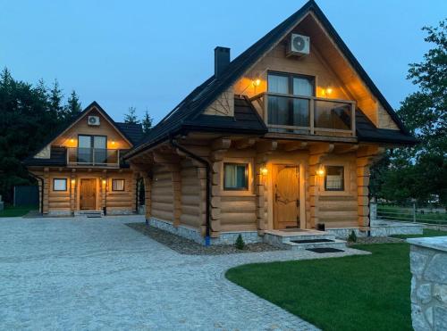 a log cabin with a driveway in front of it at Bałtowska Osada in Bałtów