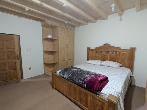 a bedroom with a large bed with a wooden headboard at Passu Didargah Resort in Pasu