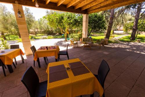 patio ze stołami, krzesłami i drzewami w obiekcie Agriturismo Monte degli Angeli w mieście Serrano
