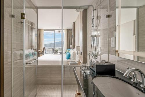 a bathroom with a shower and a sink and a bed at Crystal Bay Premier Suites in Nha Trang