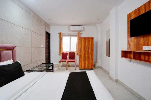 ein Schlafzimmer mit einem Bett und zwei roten Stühlen in der Unterkunft Super Collection O Taramandal Road Gorakhpur Formerly NS Hotel in Gorakhpur