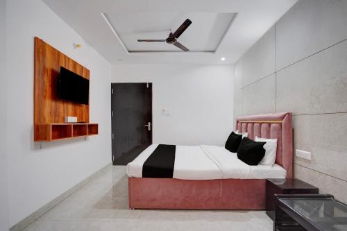 ein Schlafzimmer mit einem Bett und einem Fernseher an der Wand in der Unterkunft Super Collection O Taramandal Road Gorakhpur Formerly NS Hotel in Gorakhpur