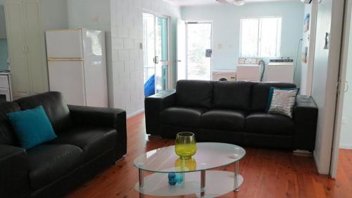 a living room with two black couches and a glass table at Lanas Cottage in Arcadia