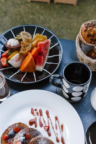 a table with two plates of food and a cup of coffee at Hotel Vibe Blu Near JHV Mall in Varanasi