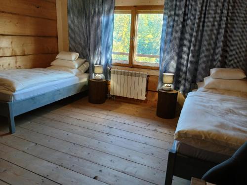 two beds in a room with a window and two lamps at Bauernhaus in Dzianisz