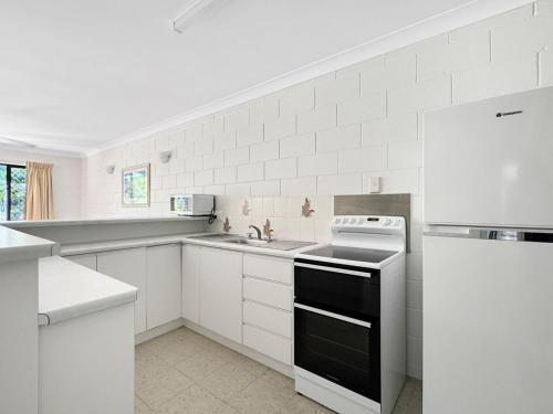a white kitchen with a stove and a sink at Arcadia Palms 1 in Arcadia