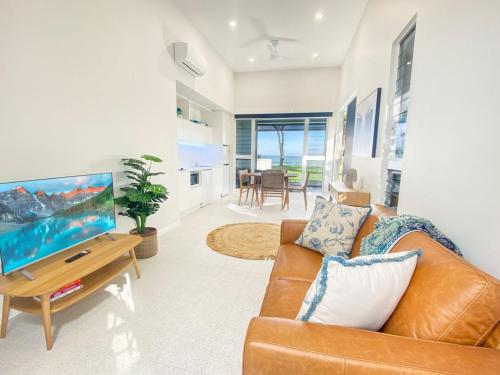 a living room with a couch and a flat screen tv at Rock Salt Villa 1 in Picnic Bay