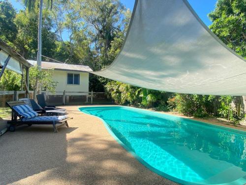a swimming pool with two chairs next to a house at The Barracks Arcadia 2 in Arcadia