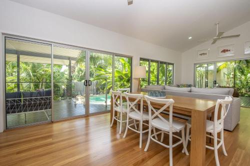 a dining room with a table and chairs and a couch at Whispering Palms in Nelly Bay