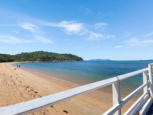 a beach with a white fence and the ocean at Kadani in Picnic Bay