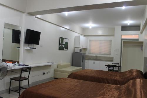 マニラにあるRESIDENCIA SAN VICENTE - PASAY -Budget Hotelのベッド2台、デスク、キッチンが備わる客室です。