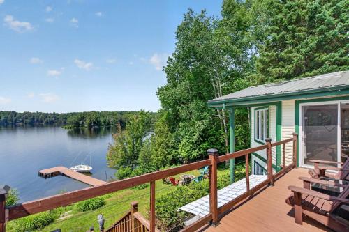 a house with a deck next to a lake at Spa & Waterfront - Chalet le Colibri in Saint-Rémi-dʼAmherst