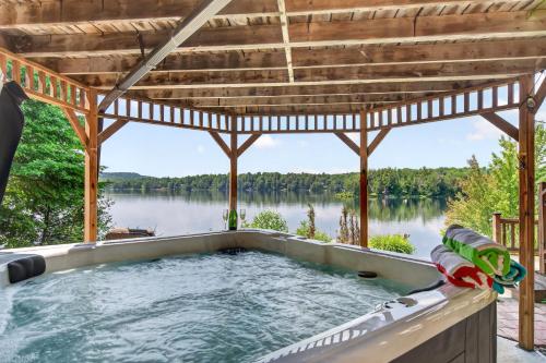 an outdoor hot tub with a view of a lake at Spa & Waterfront - Chalet le Colibri in Saint-Rémi-dʼAmherst