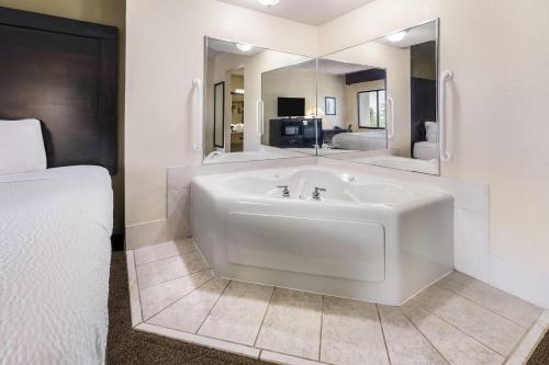 a large white bath tub in a room with a bed at Baymont by Wyndham Janesville in Janesville
