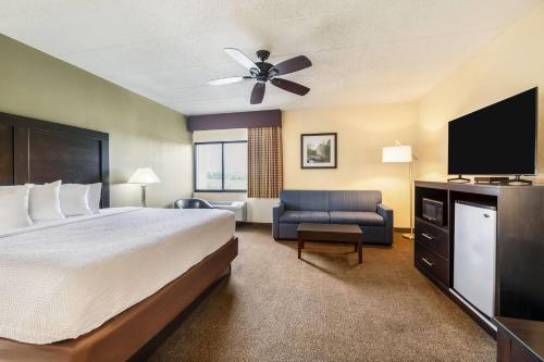 a hotel room with a bed and a flat screen tv at Baymont by Wyndham Janesville in Janesville